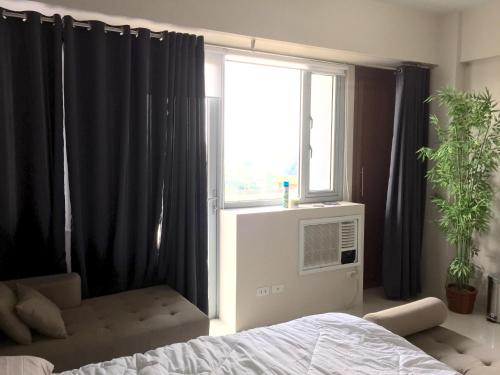 - une chambre avec un lit et une fenêtre avec des rideaux noirs dans l'établissement One Palm Tree Villa CC9N, à Manille