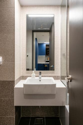 a bathroom with a white sink and a mirror at Brand New Residence with Family in Busan