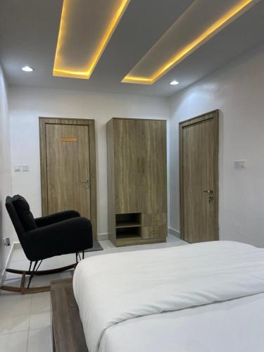 a bedroom with a bed and a black chair at Reebsah Luxury stay in Abuja