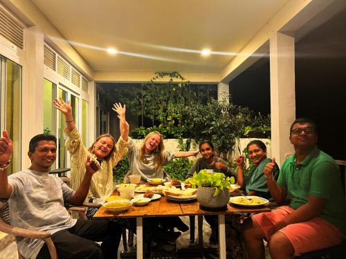 a group of people sitting at a table with their hands in the air at Pretty Villa in Gelioya