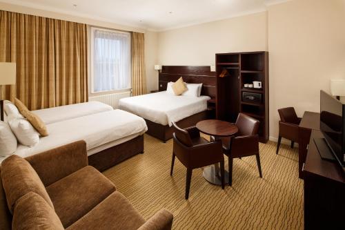 a hotel room with two beds and a couch at Mercure Maidstone Great Danes Hotel in Maidstone