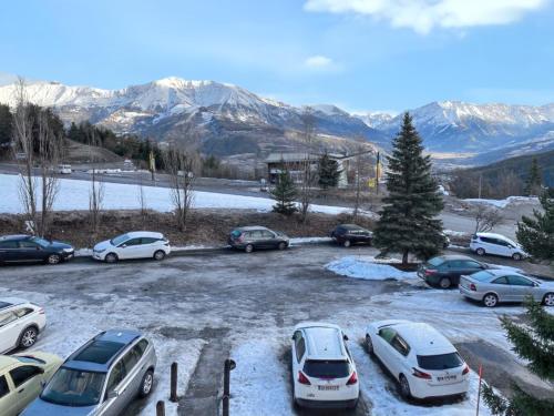 a bunch of cars parked in a parking lot with mountains at Studio cosy à Uvernet-Fours / 15 m² / Vue montagne in Uvernet-Fours