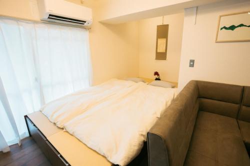 a bed in a room with a couch and a window at Tokyo Base Meguro Room #301 in Tokyo