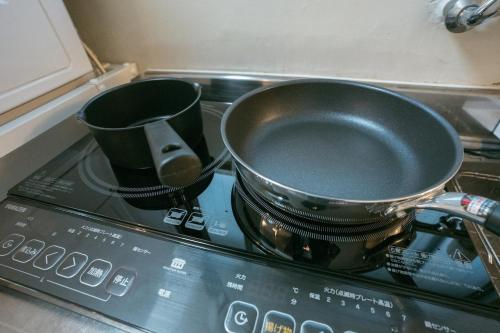 a pan and two cups sitting on top of a stove at Tokyo Base Meguro Room #301 in Tokyo