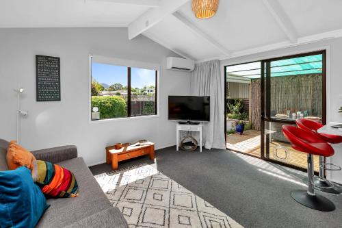 a living room with a couch and a flat screen tv at Cottage on Churchill in Whangarei