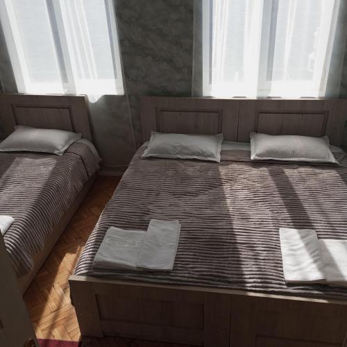 two beds in a room with two windows at B&B Villa Maurizio in Tskaltubo