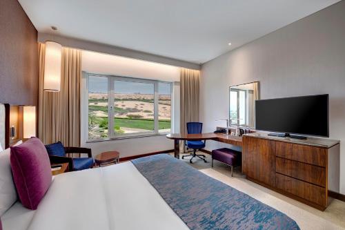 a hotel room with a bed and a flat screen tv at Crowne Plaza Muscat OCEC by IHG in Muscat