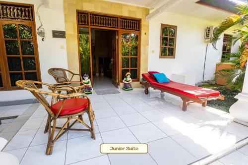 a patio with chairs and a bench and a porch at Kaia Lovina Guest House Junior Suite in Lovina