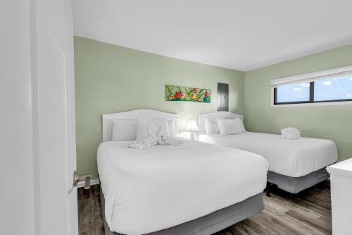 two beds in a room with white sheets at Spectacular Oceanview Condos in Myrtle Beach