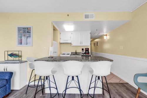 a kitchen with white cabinets and bar stools at Spectacular Oceanview Condos in Myrtle Beach