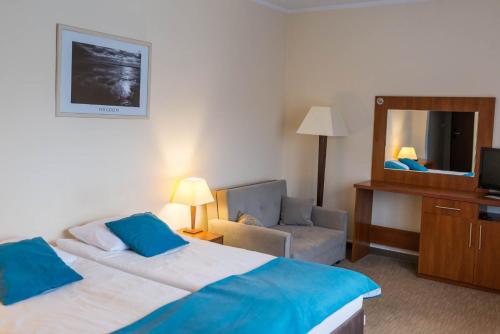 a hotel room with a bed and a chair and a mirror at Hotel Mazury in Giżycko