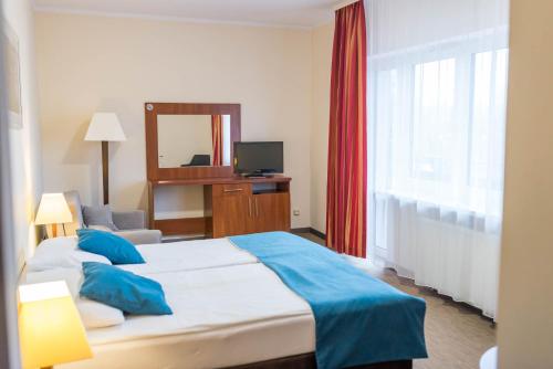 a hotel room with a large bed and a mirror at Hotel Mazury in Giżycko