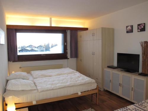a bedroom with a bed with a window and a television at Residenz Rosablanche, Fewo GENTIANES by fewo-plan SIVI155 in Siviez