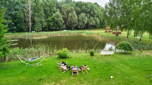 a group of people sitting in hammocks by a lake at Hotel Mazury in Giżycko