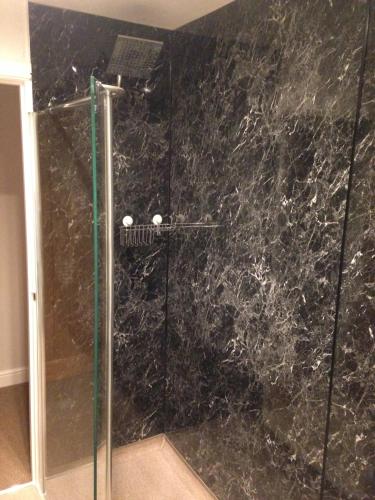 a bathroom with a shower with a black marble wall at The Wheatsheaf in Crick