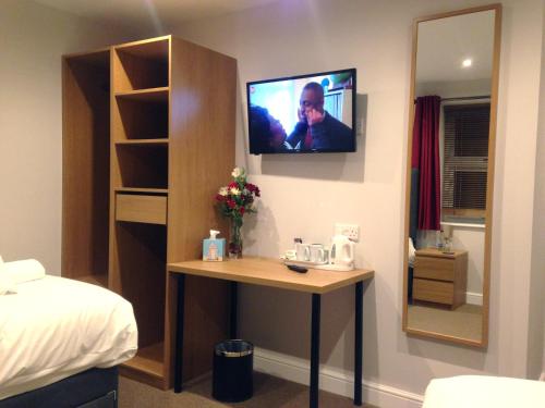 a room with a table and a tv on the wall at The Wheatsheaf in Crick