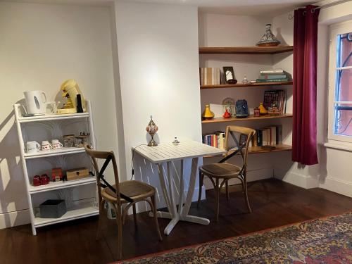 - une table et des chaises dans une pièce avec une étagère dans l'établissement Le Cazalet, à Saint-Sever