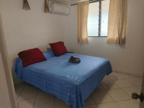 a bedroom with a bed with a blue blanket and red pillows at Fare Ara Location Huahine in Fare