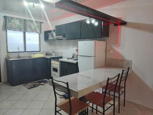 a kitchen with a table with chairs and a refrigerator at Fare Ara Location Huahine in Fare