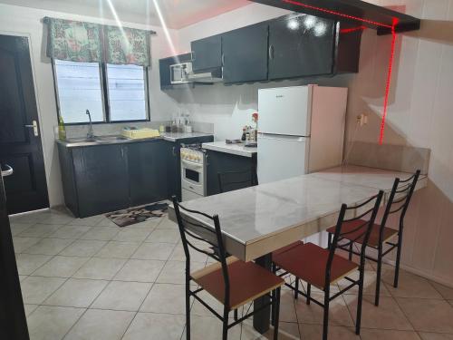 a kitchen with a table and chairs and a refrigerator at Fare Ara Location Huahine in Fare