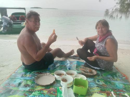 a man and a woman sitting on the beach at Amaro Homestay in Nuhu Tawun