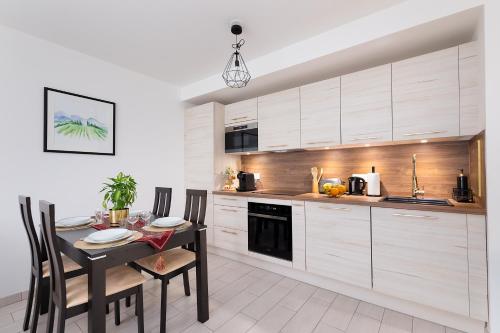 a kitchen with white cabinets and a table with chairs at Chic & Cozy Living - Near Heart of Paris in Clichy
