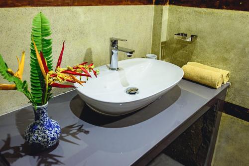 a bathroom with a sink and a vase with a plant at White on White in Hikkaduwa