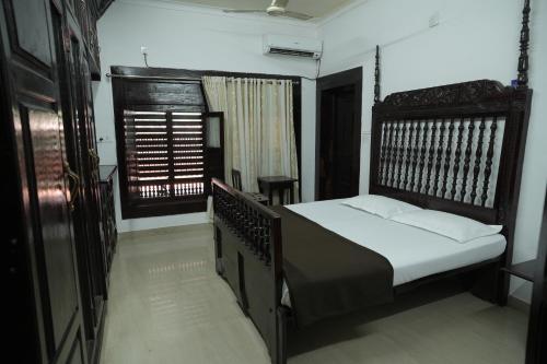 ein Schlafzimmer mit einem Bett und einem Fenster in der Unterkunft Heritage Villa in Mangaluru