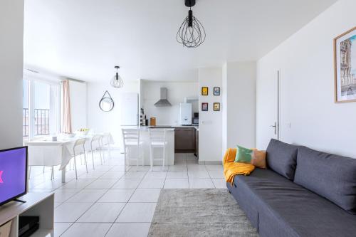 un salon avec un canapé et une cuisine dans l'établissement Magnifique vue sur la Tour Eiffel - Paris 10mn - Parking - métro 2min - Privé - balcon, à Saint-Ouen