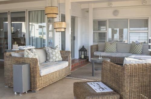 un porche con muebles de mimbre en una casa en Seeplaas Beach House, en Mossel Bay