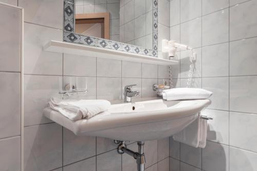 a white bathroom with a sink and a mirror at SCHMID Rooms & Apartments in Ischgl