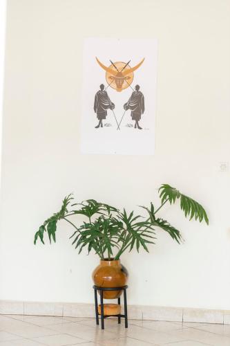 a plant in a vase next to a clock on a wall at Inkindi House in Kigali