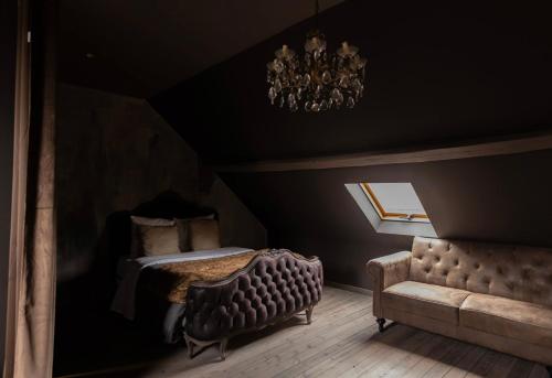 a bedroom with a bed and a couch and a chandelier at Le 1930 in Hénin-Beaumont