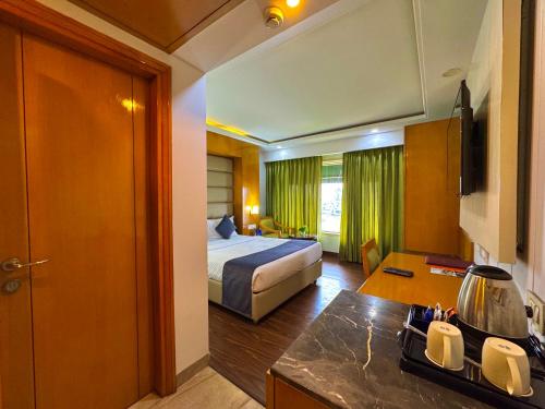 una camera d'albergo con letto e scrivania con cucina di GMS Grand Boutique Hotel ( A Unit of GMC Hotel & Resorts) a Dehradun