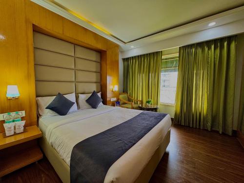 una camera da letto con un letto grande e una finestra di GMS Grand Boutique Hotel ( A Unit of GMC Hotel & Resorts) a Dehradun