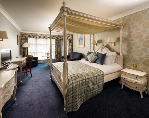 a bedroom with a canopy bed and a desk at Mercure Bristol North The Grange Hotel in Bristol