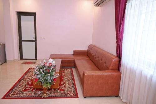 a living room with a brown leather couch and a table at Khách sạn Hoàng Hà River Town in Yên Bái