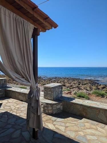 a patio with a curtain next to the beach at Seaside Apartment in Agios Nikolaos