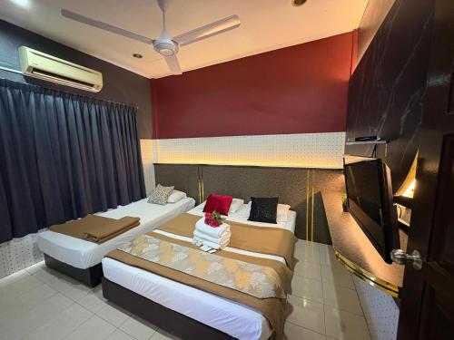 a hotel room with two beds and a flat screen tv at Weng Kong Hotel in Slim River