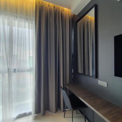 a room with a desk and a window with a mirror at Urban Suites - Queens Suite in Jelutong