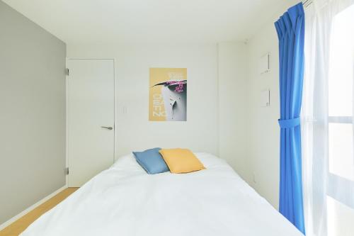 a bedroom with a white bed with blue curtains at Ruygo Setagaya in Tokyo