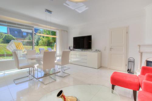 a living room with a table and chairs and a tv at Windeby 1T in Wenningstedt
