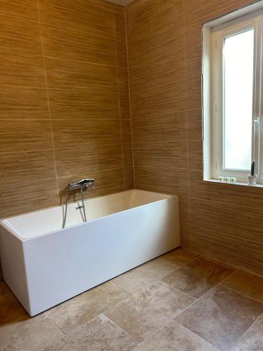 - une baignoire blanche dans une chambre avec fenêtre dans l'établissement Maison Hortense Carcassonne, à Carcassonne