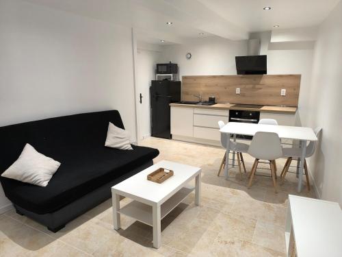 a living room with a black couch and a kitchen at Appartement avec une chambre et tout équipé dans centre ville in Montélimar