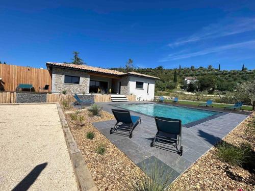 - une piscine avec 2 chaises en face d'une maison dans l'établissement Villa la crozette 4 étoiles, climatisée avec grande piscine, à Ruoms