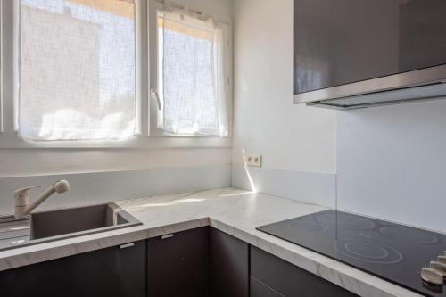 une cuisine blanche avec un évier et une cuisinière dans l'établissement Le Vélodrome à 5 minutes à pieds du stade, à Marseille