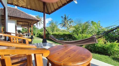 a hammock and a table and chairs on a patio at Frangipani Inn & Restaurant in Seraya