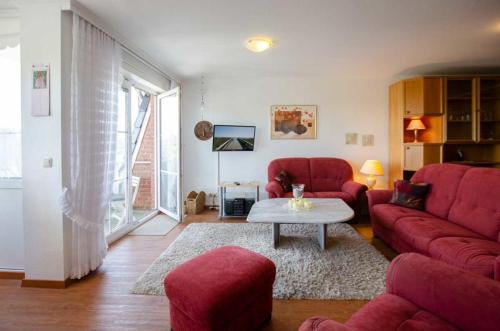 a living room with a red couch and a table at FeWo Krüger 19 in Dahme