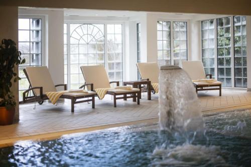 a fountain in a room with chairs and a pool at Romantikhotel Platte in Attendorn