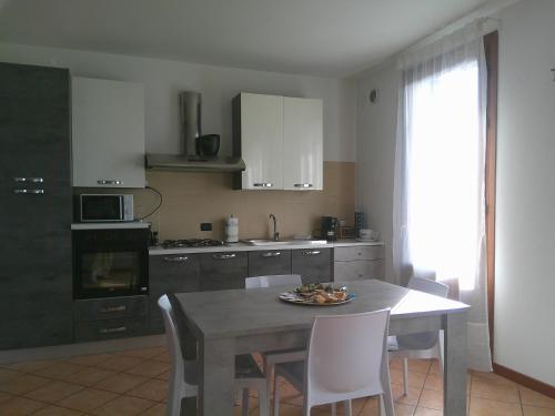 a kitchen with a table and white chairs and a table and a kitchen with at Appartamenti Euganea - Rovolon in Rovolon